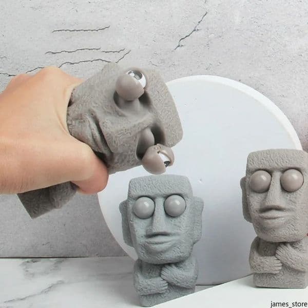 Stone man releases stress toy slowly rebounds soft tpr Moai statue squeeze eyes interested expression relaxes stress gift